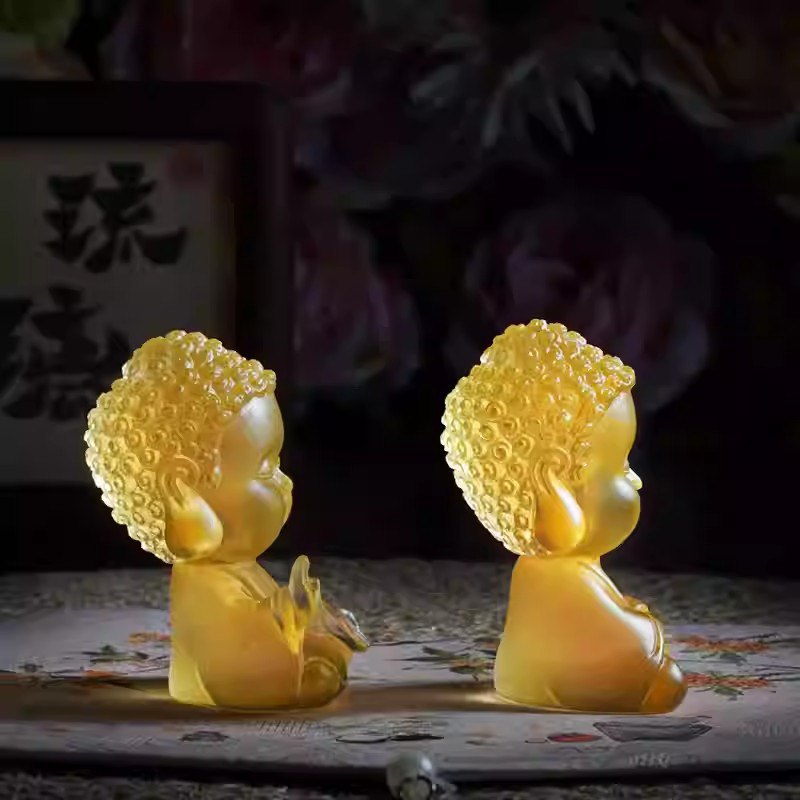 A pair of serene yellow translucent Buddha tea pets, captured from a side profile under soft lighting to highlight their peaceful Zen aesthetic.