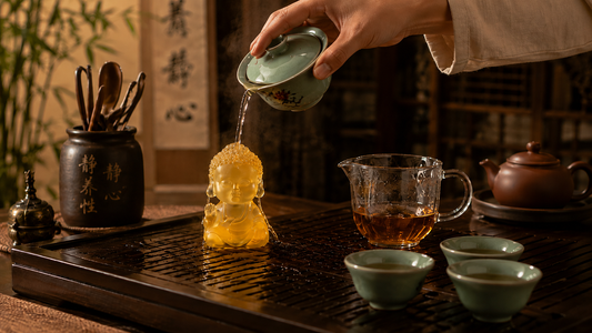Amber Chinese liuli Baby Buddha tea pet being rinsed with tea during a traditional Gongfu tea ceremony.