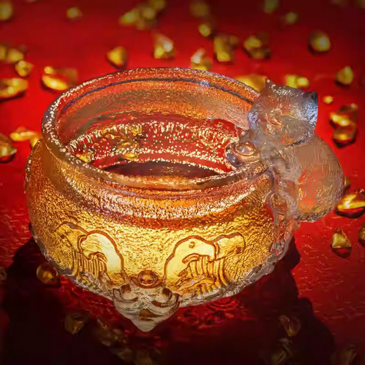 Artistic embossed glass teaware featuring intricate traditional patterns and a playful kitten, showcasing premium craftsmanship and brilliant light reflections.