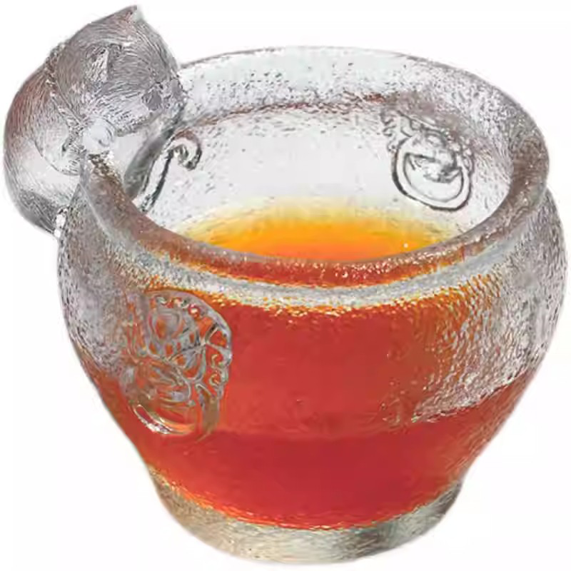 A premium handcrafted glass teacup with a playful cat figurine, featuring a sparkling hammered texture and traditional relief patterns on a clean white background.