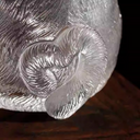 Macro close-up of a handcrafted glass teacup showing the intricate fur-like texture and a cute curled cat tail detail.