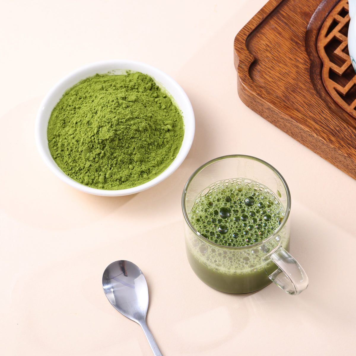 Fine green matcha powder with freshly prepared matcha in a clear glass cup.