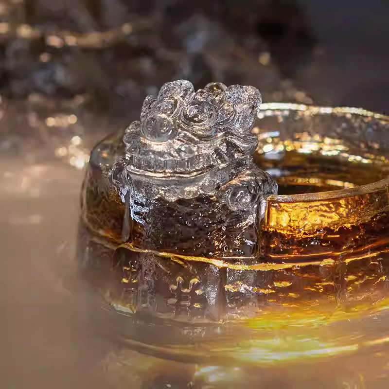 An ethereal scene featuring a glass guardian lion teacup enveloped in natural mist, highlighting its Great Wall texture and glowing golden tea.