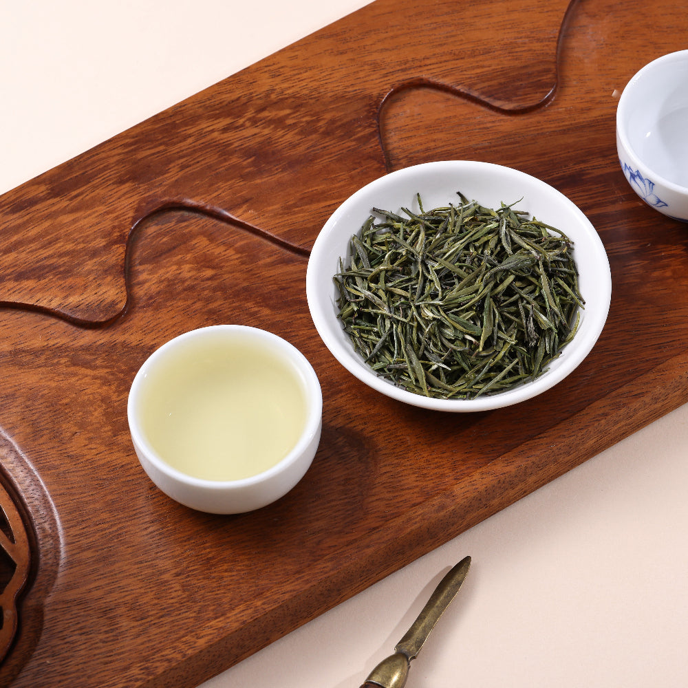 Premium Gongya Green Tea from China, featuring delicate loose leaf tea buds and a fresh light green tea infusion on a traditional tea tray