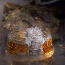 An exquisite crystal-clear glass teacup featuring a mythical guardian lion sculpture on a Great Wall textured base, glowing with golden tea.