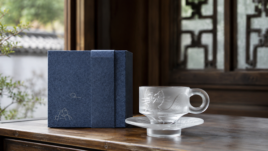 Handcrafted Chinese liuli glass tea cup with matching saucer and premium gift box displayed in an elegant traditional tea room.