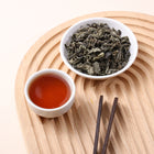 Laifeng loose leaf vine tea with dried leaves and reddish amber tea liquor on a natural wooden tray.