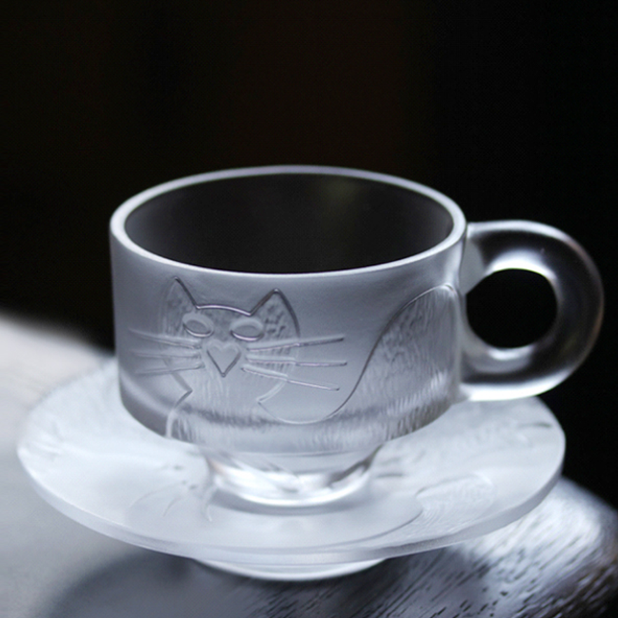 A stylish frosted glass cup and saucer set featuring a minimalist cat relief design, showcasing a sleek and modern aesthetic with a comfortable circular handle.