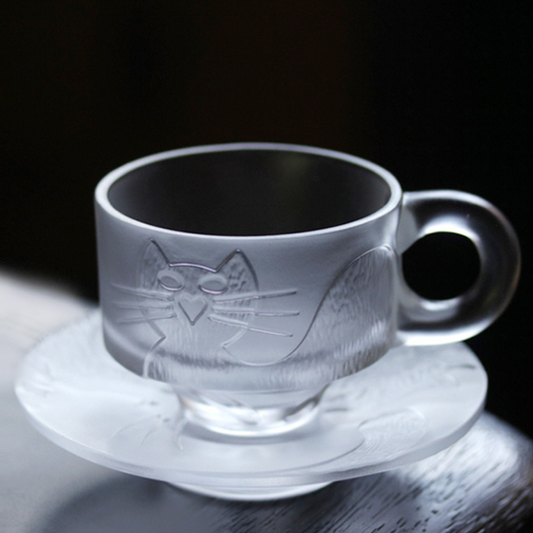 A stylish frosted glass cup and saucer set featuring a minimalist cat relief design, showcasing a sleek and modern aesthetic with a comfortable circular handle.