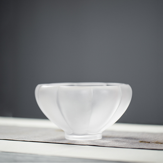 A minimalist frosted glass teacup with an elegant ribbed design and petal-shaped silhouette, showcasing a clean and peaceful Zen aesthetic.
