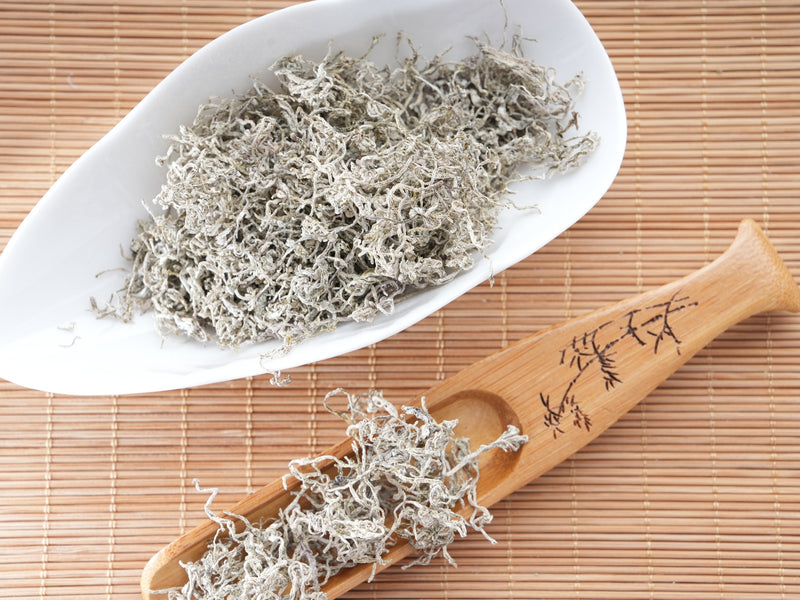 Premium Laifeng Vine Tea dried leaves with natural white frost-like flavonoid crystals displayed on a bamboo tray