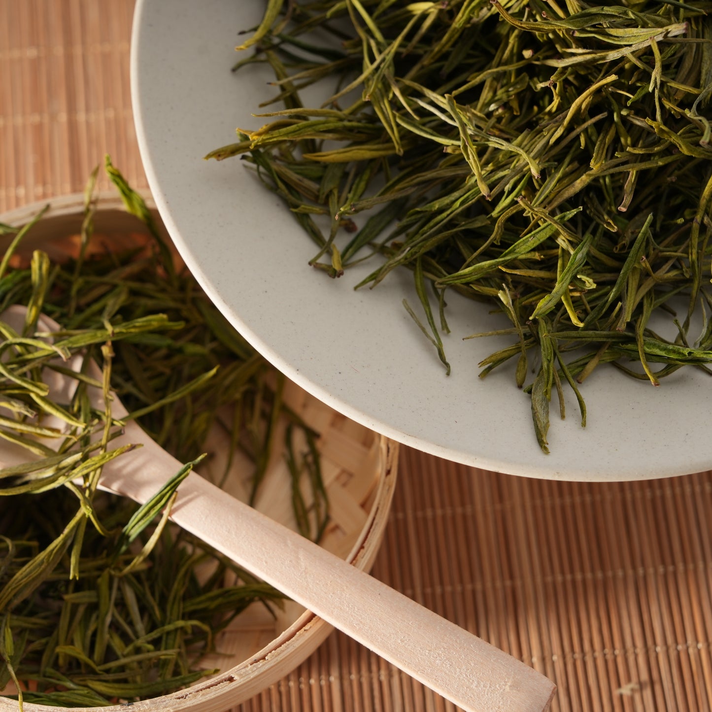 Premium SeTeng loose leaf white tea featuring delicate, straight needle-like buds, elegantly displayed in a white ceramic bowl and bamboo basket.