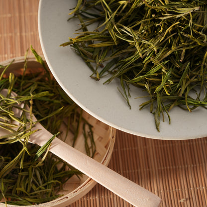 Premium SeTeng loose leaf white tea featuring delicate, straight needle-like buds, elegantly displayed in a white ceramic bowl and bamboo basket.