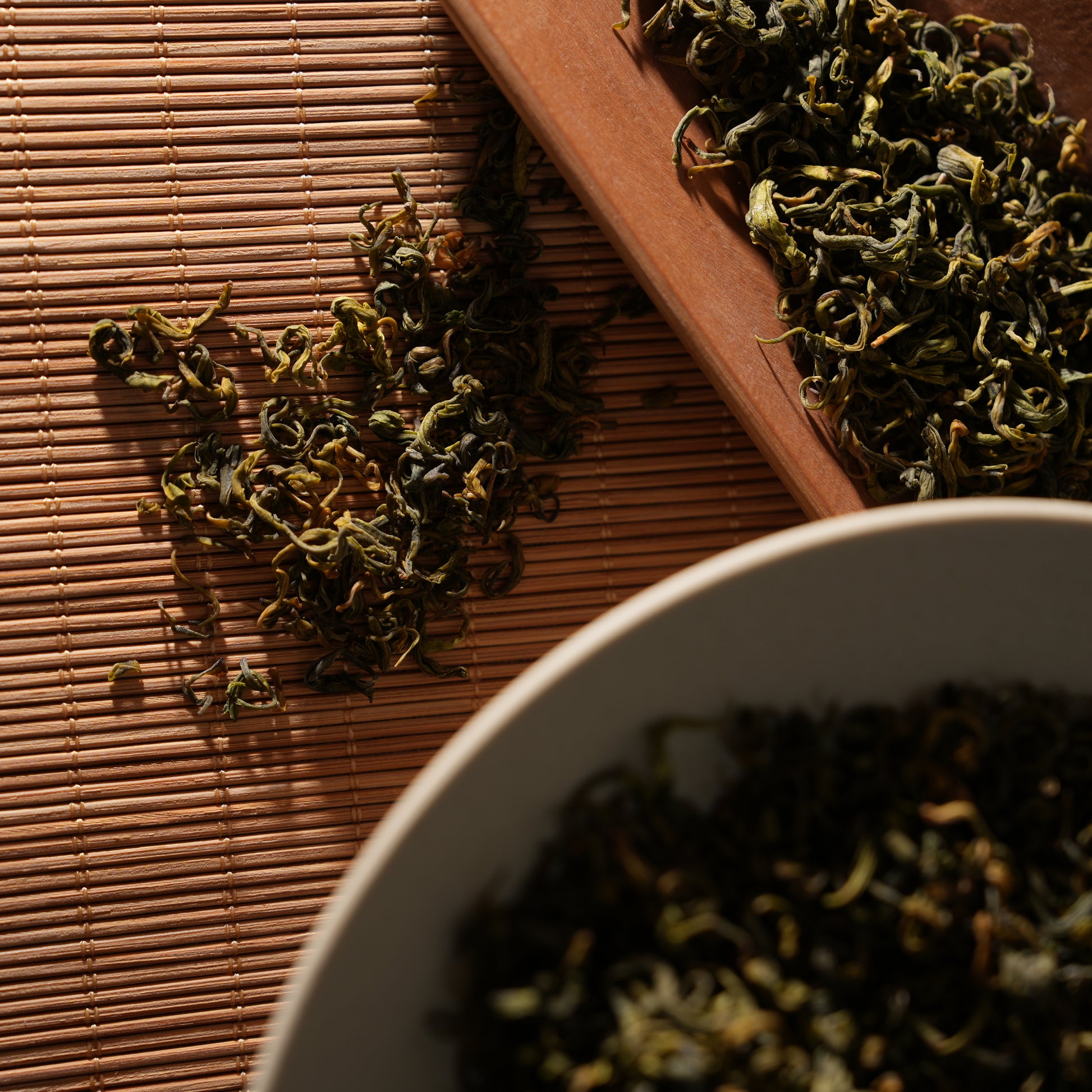 SeTeng premium loose leaf white tea with beautifully twisted leaves, elegantly displayed on a rustic bamboo mat and wooden scoop.