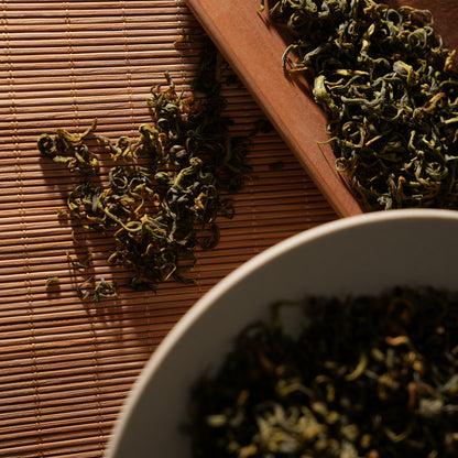 SeTeng premium loose leaf white tea with beautifully twisted leaves, elegantly displayed on a rustic bamboo mat and wooden scoop.