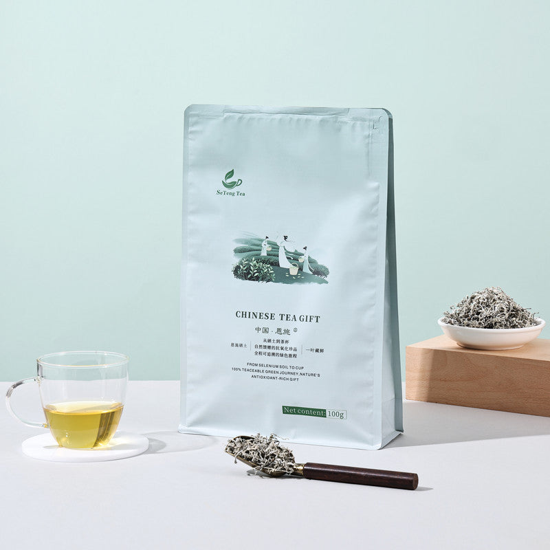 SeTeng Tea 100g pouch of premium Enshi Vine Tea, beautifully displayed with a freshly brewed glass cup and dry loose leaves on a wooden scoop.