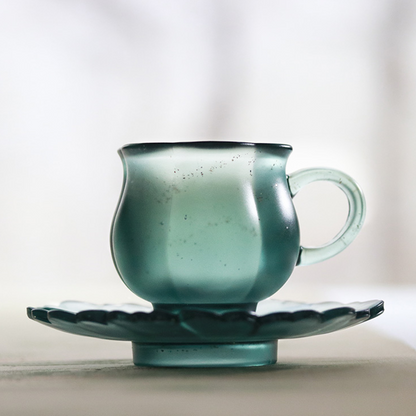High-end teal matte glass teacup set with a petal-shaped saucer, reflecting a serene and luxurious light diffusion through its unique misty texture.
