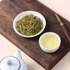 Xianfeng milk white green tea with slender dried leaves and pale golden tea liquor.